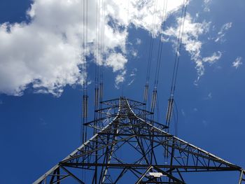 Low angle view of electricity pylon against blue sky