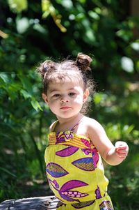 Girl looking away while standing by plants in park