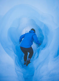 Rear view of woman walking in ice cave