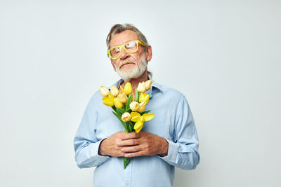 Portrait of young woman holding flower against white background