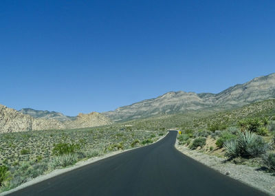 Road amidst mountains against clear blue sky