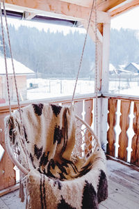 Cozy outdoor swing chair on the wooden terrace in the mountains holiday home in winter