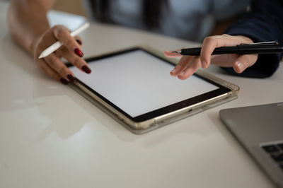 Midsection of woman using mobile phone on table