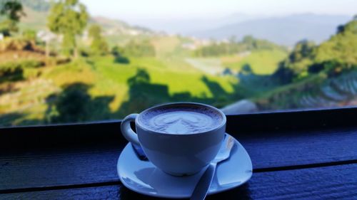 Close-up of coffee cup on table against window