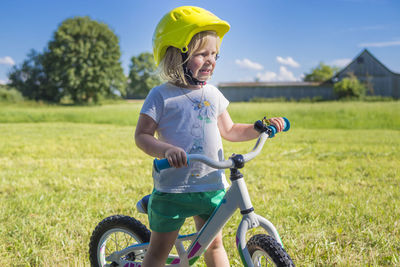 Girl with bicycle on grassy field