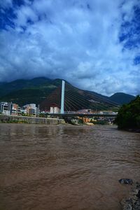 Scenic view of river by buildings in town against sky