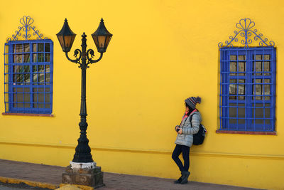 Woman standing against yellow building