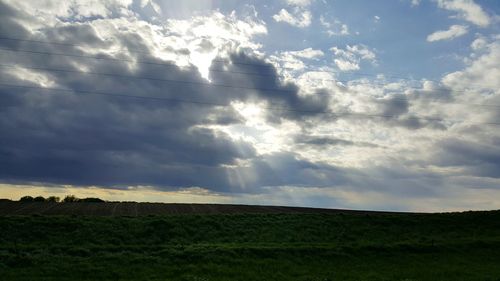 Scenic view of grassy field against cloudy sky