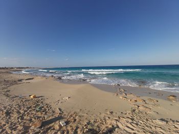 Scenic view of beach against clear blue sky