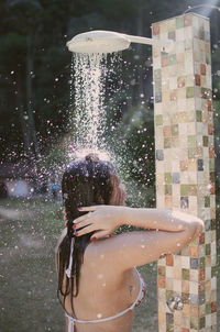 Rear view of woman taking a bath outdoors