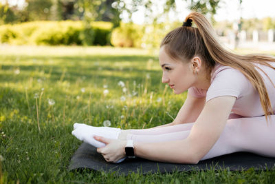 Athletic girl doing a warm-up on a fitness mat in the park
