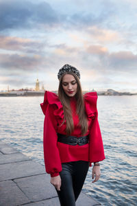 Portrait of beautiful young woman standing in water against sky