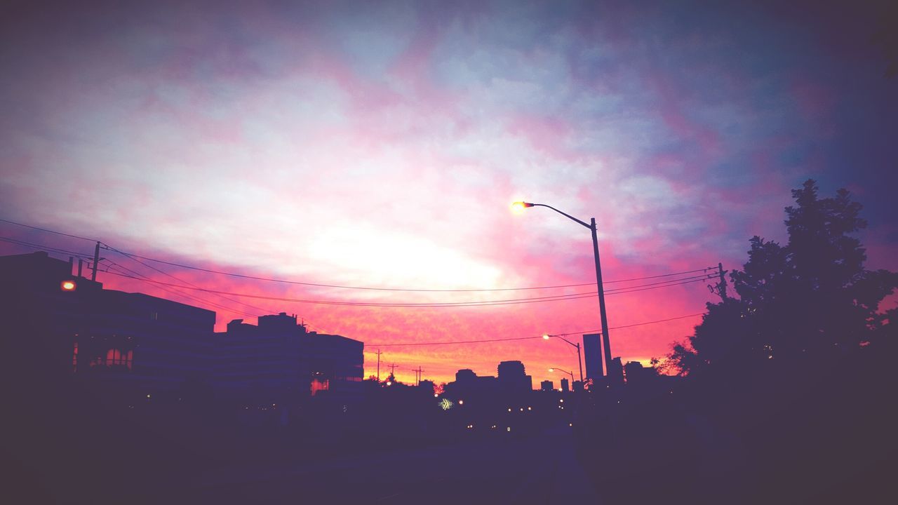 sunset, building exterior, silhouette, sky, architecture, built structure, street light, city, low angle view, cloud - sky, car, orange color, street, transportation, dusk, cloud, road, building, outdoors, no people