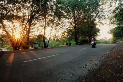 Road amidst trees against sky during sunset