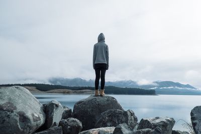 Rear view of man standing on rock against sea