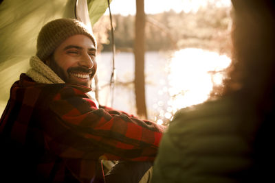 Side view of happy man looking at female friend during camping