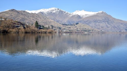 Scenic view of lake by snowcapped mountains against sky