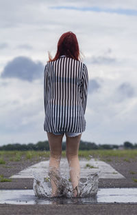 Rear view of woman jumping on water against sky