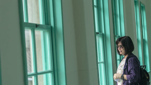 Young woman looking through window