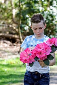 Close-up of boy holding flower against blurred background