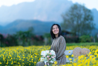 Portrait of a smiling young woman standing on field