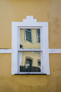 Low angle view of yellow window on wall of building