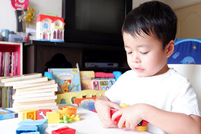 Cute boy playing with toys on table at home