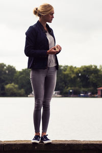 Woman standing on retaining wall against sky