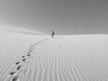 Toddler walking on desert against sky during sunny day