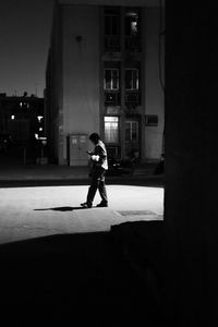Man walking on street against building at night