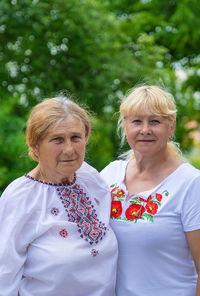 Portrait of smiling friends standing against trees