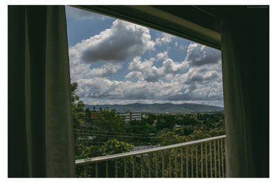 Scenic view of landscape against sky seen through window