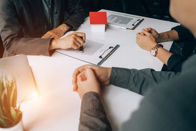 Midsection of man holding paper while sitting on table