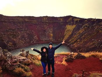 Full length of friends standing on rock formation against sky