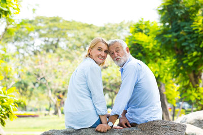 Happy couple sitting on rock at park