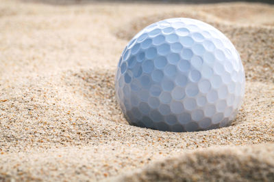 Close-up of golf ball on sand