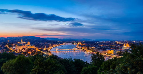 High angle view of illuminated city against cloudy sky