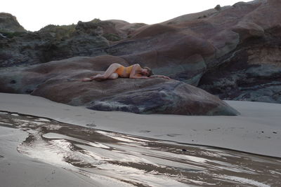 Woman laying on the rock at the beach