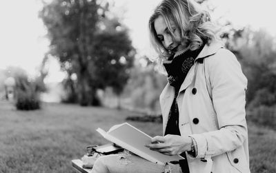 Woman reading book on field during winter