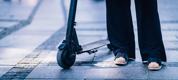 Low section of woman with push scooter standing on road