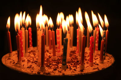 Close-up of many candles on birthday cake in dark