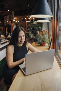 Young woman using laptop on table in cafe