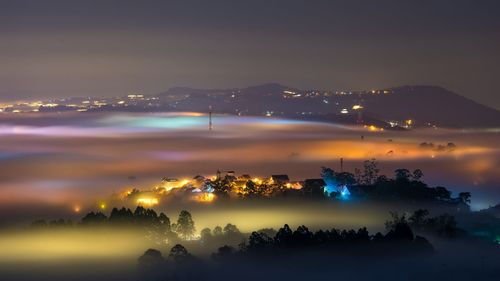 Illuminated cityscape against sky at night