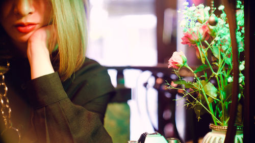 Portrait of woman standing by potted plant