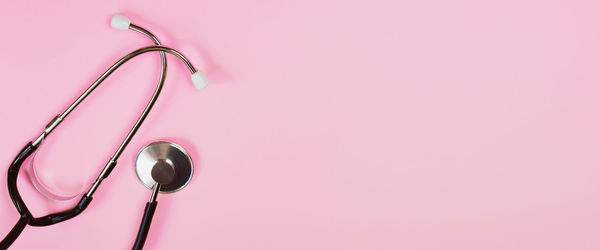 Directly above shot of stethoscope against pink background