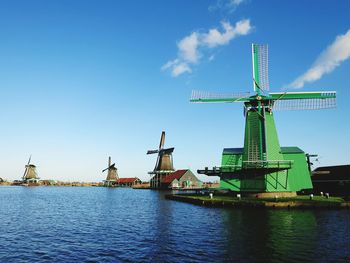 Windmills by river against sky