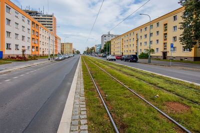 Road by buildings in city against sky