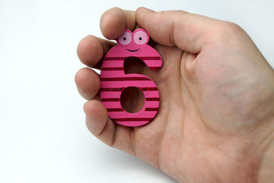 Close-up of hand holding toy over white background