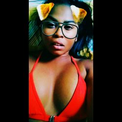 Close-up portrait of young woman standing against black background