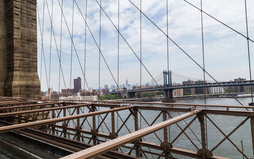 Manhattan bridge over east river against sky seen from brooklyn bridge